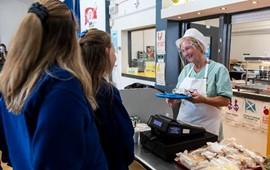 Image of two school pupils in the canteen being served by a Catering Assistant 